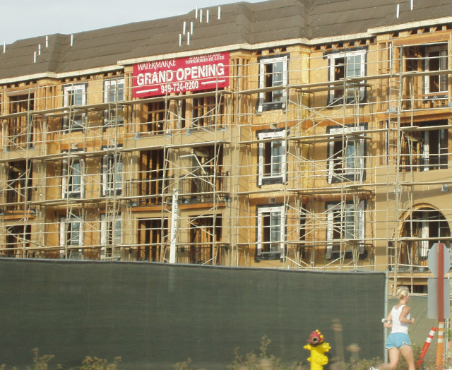 Half-finished apartment building with 'Grand Opening' banner.