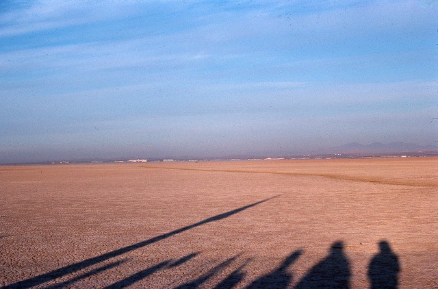 Shadows stretch across a dry lake bed.