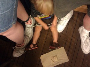 Toddler on the floor, ready to tie his parents' shoes together.