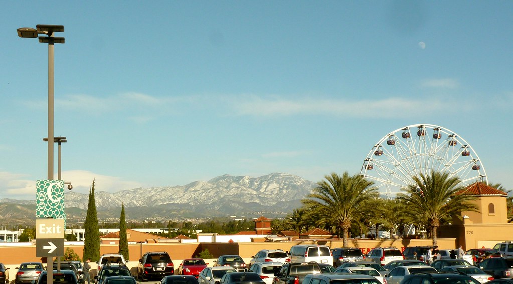 Mt Saddleback covered with snow. A Ferris Wheel and parking lot with cars in the foreground.