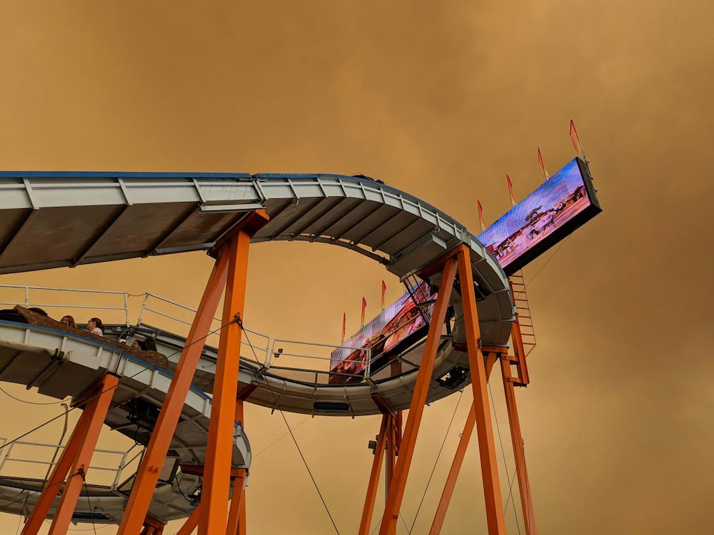 [Looking up at a log ride against clouds of brownish smoke.]