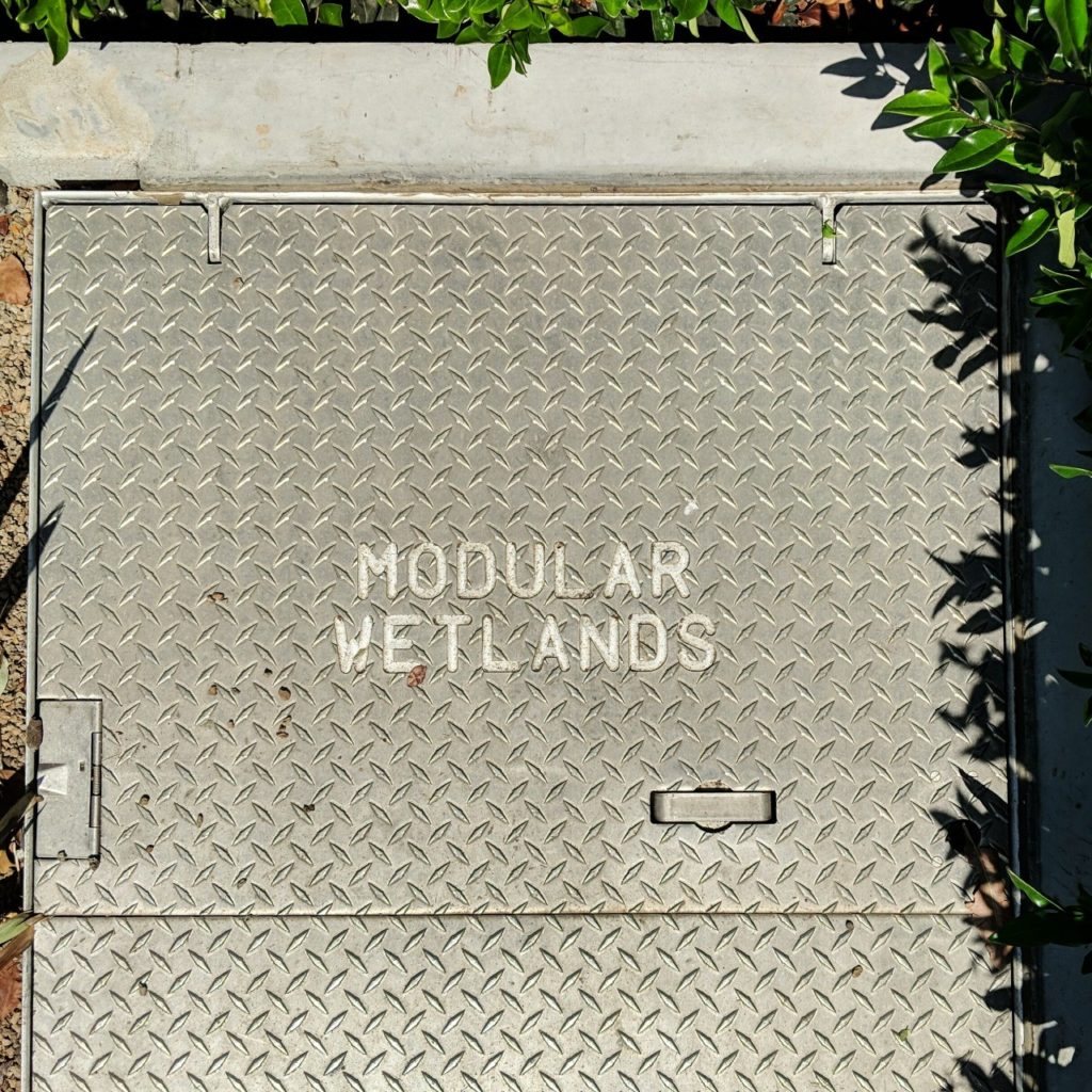 [Metal hatch on the ground labeled MODULAR WETLANDS]