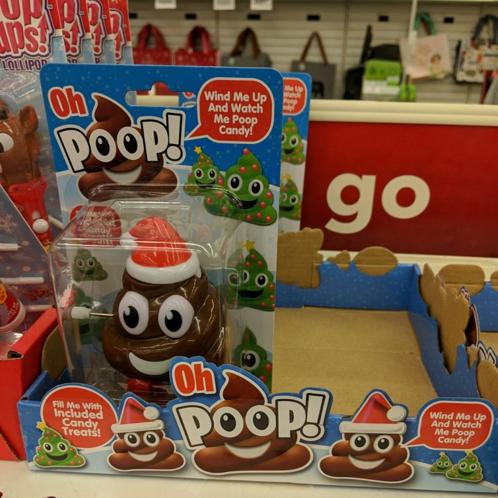 A poop emoji candy dispenser that poops out poop-emoji candy, on a store shelf next to the word GO.