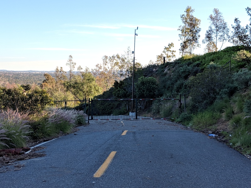 A gate across a two-lane road heading downward through the hills.