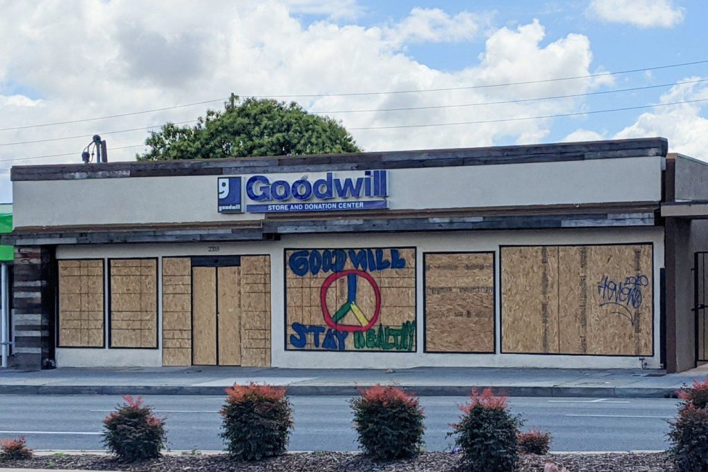 Goodwill store with plywood all over the front. Someone has painted STAY HEALTHY on the plywood.