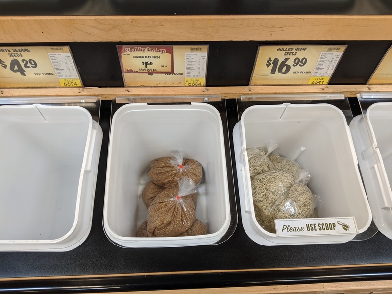Bulk bins at the supermarket with pre-measured plastic bags of grains in them.