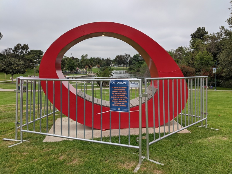 Red gate/ring sculpture/bench with a fence around it.